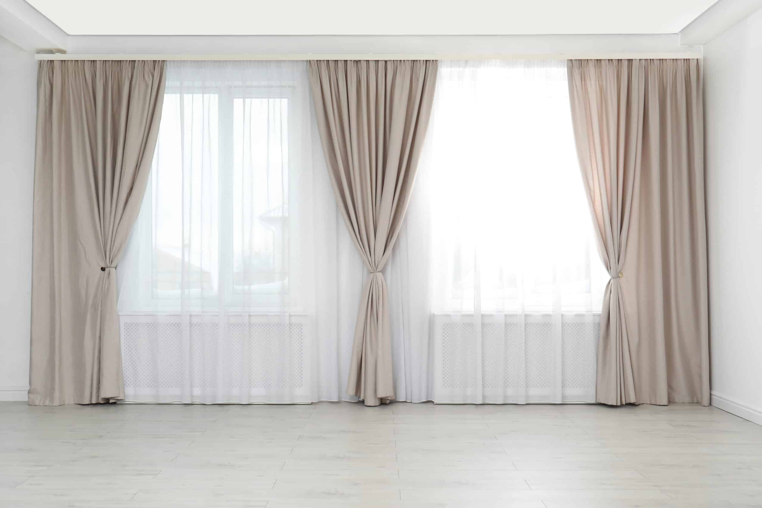 Floor-length beige curtains layered over sheer white curtains