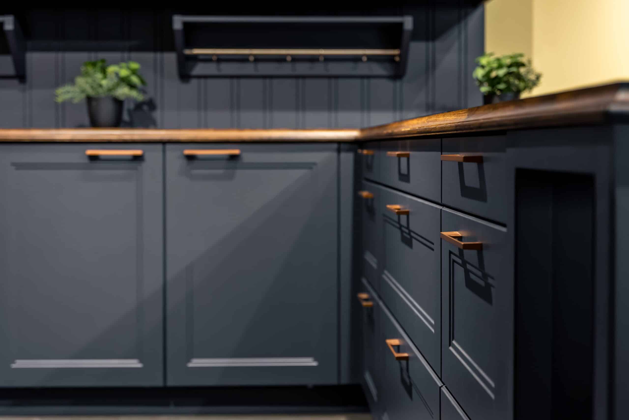 Dark kitchen cabinets with copper handles and wooden worktops